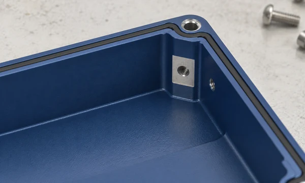 Conceptual coated enclosure corner with an uncoated metal contact pad, threaded opening and gasket land